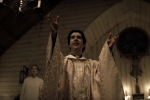 priest in a white robe on the pulpit with open arms