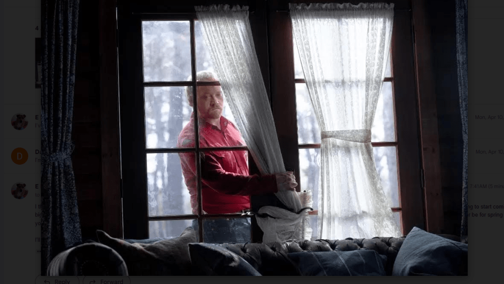 a man stands outside a window looking into a home