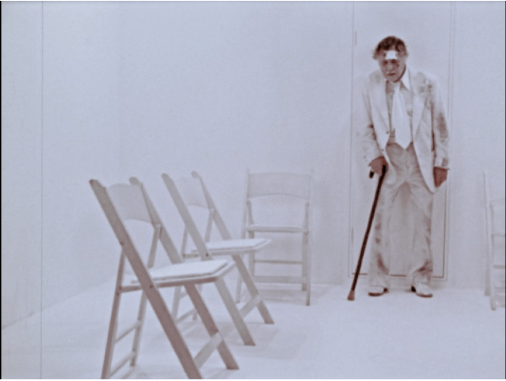 elderly man in a white suit in a sterile, white room
