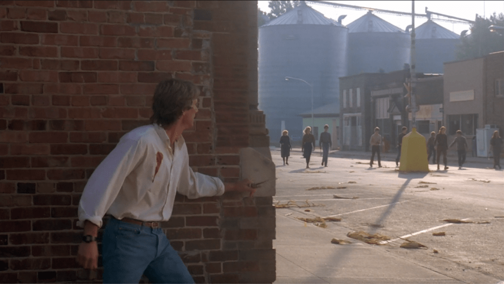 a man hides behind a wall from a group of homicidal children
