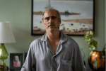 A disheveled man wearing pajamas looks concerned